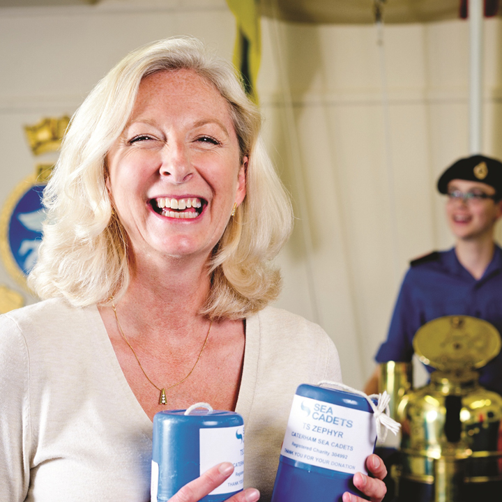 Smiling woman holding a Sea Cadet charity collection box